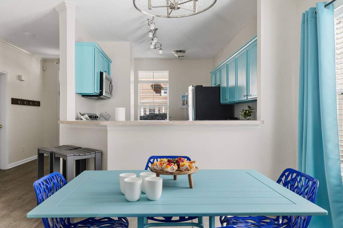 Breakfast table with blue chairs beside the teal kitchen